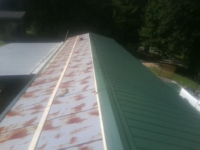 Old rusted panels beside newly installed green metal roofing — Wind Damage Roof Repair by Roofing Brothers in Inman